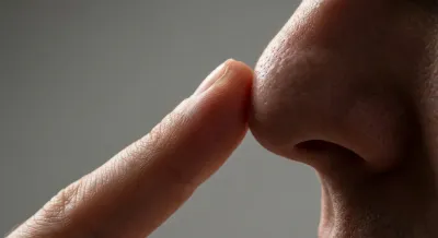 Gros plan d'un doigt touchant le bout du nez, style minimaliste et contrasté.