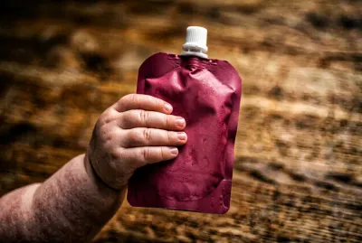 Gros plan sur une petite main tenant une gourde de compote