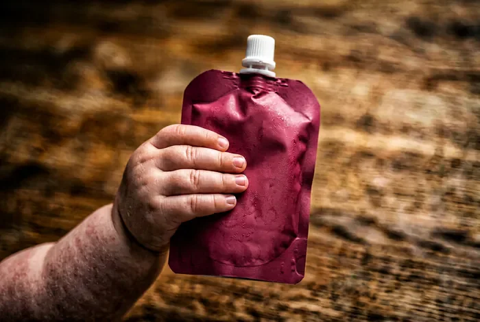 Pom'potes à partir de quel âge pour un bébé Gros plan sur une petite main tenant une gourde de compote