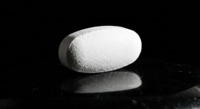 Gros plan minimaliste d'un comprimé médical sur fond sombre élégant.