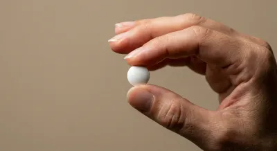 Gros plan d'un comprimé de Sawis tenu avec délicatesse