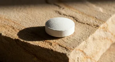 Gros plan iconique d'un comprimé de sertraline 100mg sur une surface minérale.
