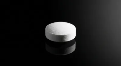 Gros plan iconique d'une pilule Slinda sur fond sombre.