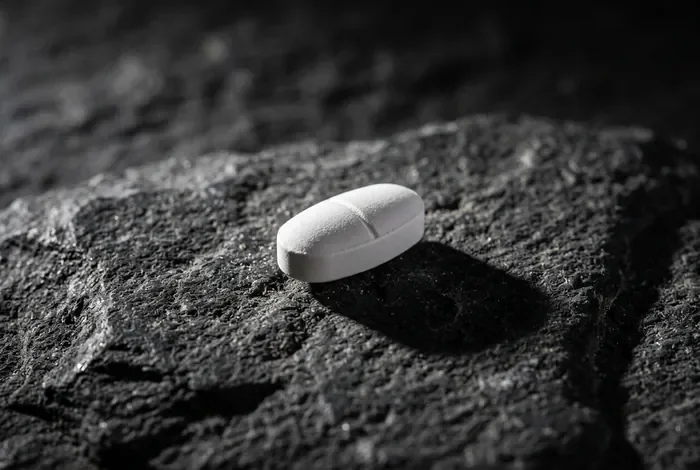 Tamoxifène et prise de poids : explications et gestion Gros plan minimaliste d'un comprimé sur une surface texturée.