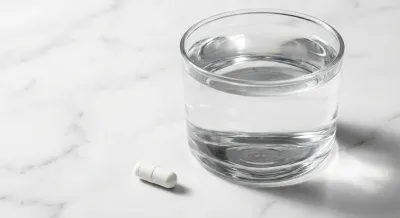 Gros plan minimaliste d'un verre d'eau et d'un comprimé sur marbre