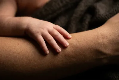Gros plan sur la main d'un bébé posée sur la peau de sa mère