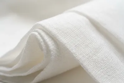 Gros plan minimaliste sur une texture textile de haute qualité, évoquant la discrétion et le confort médical.