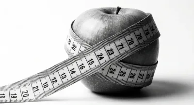 Mètre ruban autour d'une pomme verte fraîche sur fond blanc, symbole de perte de poids.