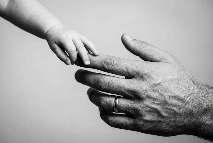 Mon bébé de 3 mois rejette papa : causes et solutions Gros plan sur la main d'un père et la main d'un bébé