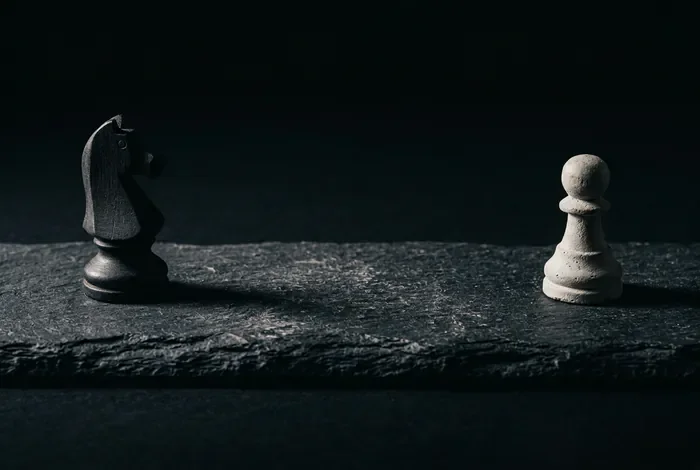 Gérer le décalage intellectuel dans un couple en 2026 Deux pièces d'échecs espacées sur une surface sombre pour symboliser le décalage dans le couple.