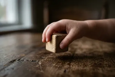 Gros plan symbolique d'un enfant jouant seul avec un bloc en bois.
