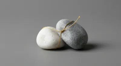 Deux pierres reliées par un fil d'or symbolisant l'attachement fragile