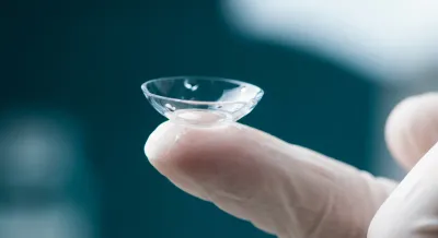 Gros plan iconique d'une lentille sclérale sur un doigt.