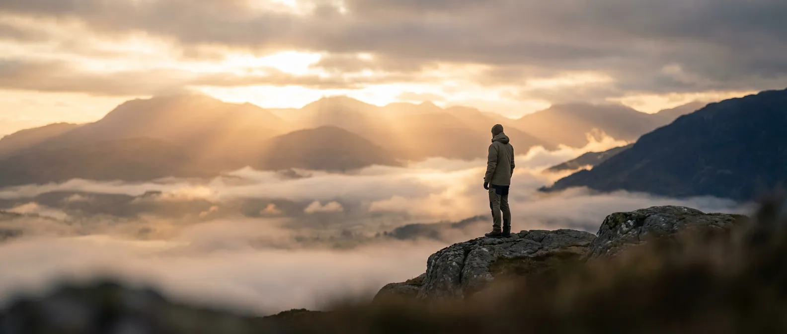 Une personne au sommet d'une montagne au lever du soleil symbolisant la guérison et l'espoir